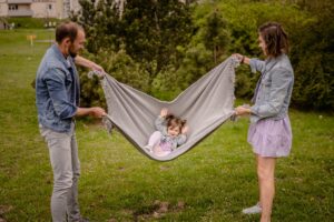 plenerowa sesja rodzinna, zabawa z kocem, rodzice, dziewczynka, Koszalin, Barbara Rompska,