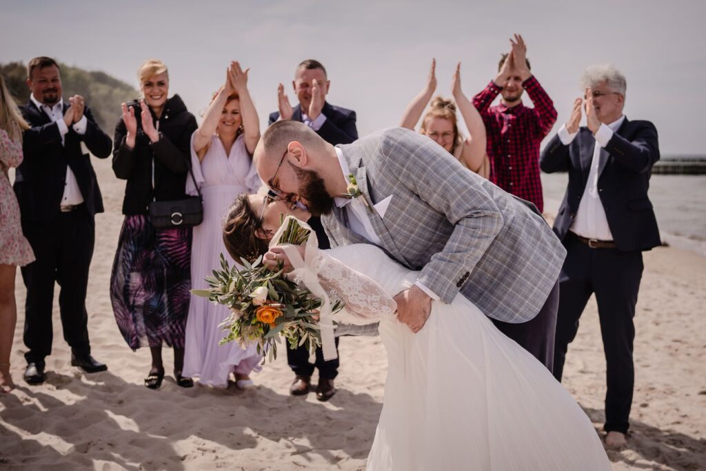 ślub na plaży, Ustronie Morskie, Barbara Rompska, fotograf Koszalin,  ślub cywilny  plenerowy, para młoda, nowożeńcy, pocałunek, goście weselni