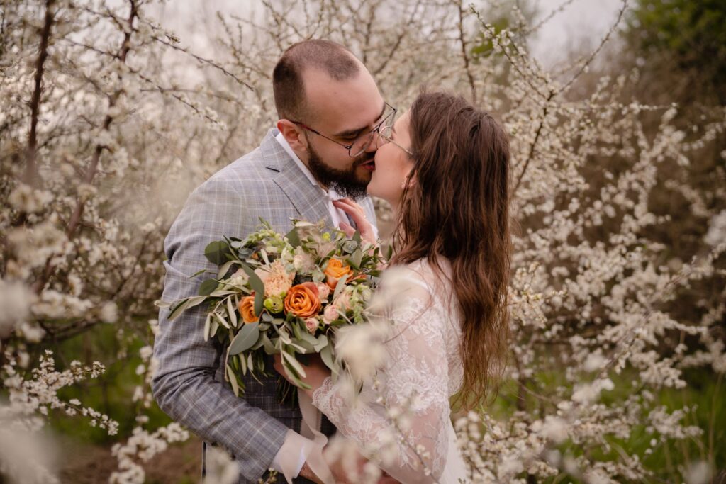 sesja ślubna, plener, kwitnące krzewy Barbara Rompska, fotograf Koszalin, pocałunek, bukiet,