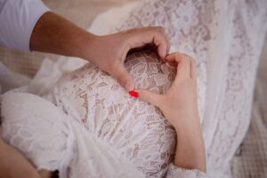 sesja ciążowa, koronkowa sukienka, brzuch ciążowy, serce z dłoni, fotograf Koszalin, Barbara Rompska